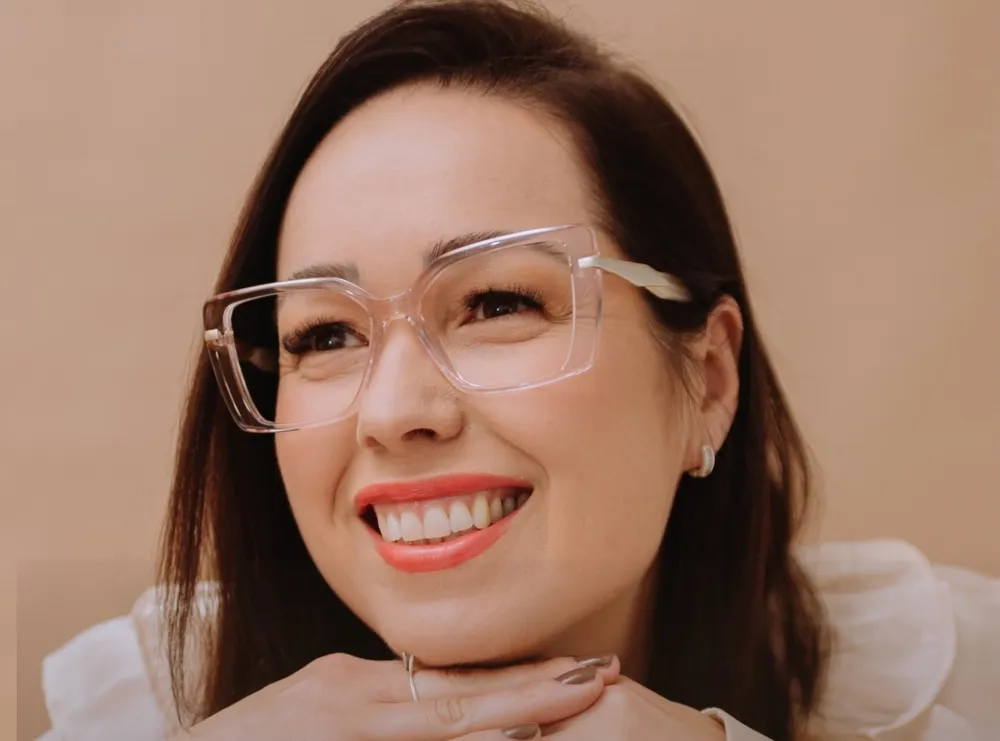 Pri, da Pri Place Ótica, sorrindo com uma armação transparente